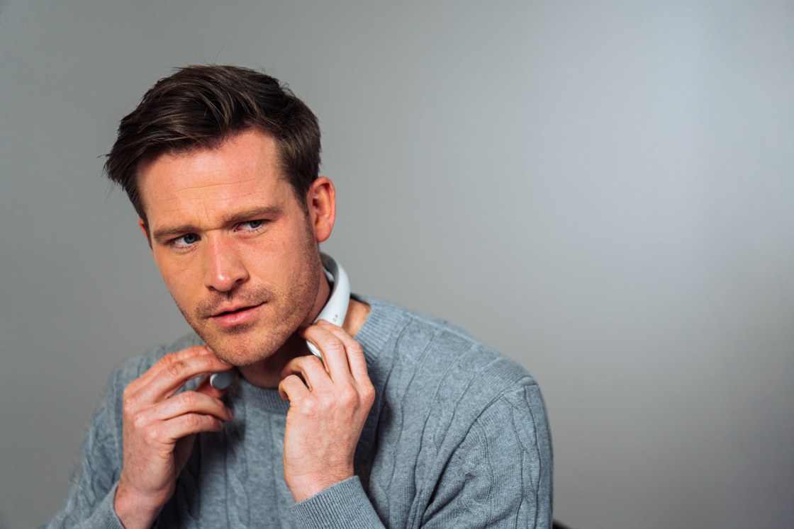 Model in a blue-grey jumper adjusting Professional X at the neck