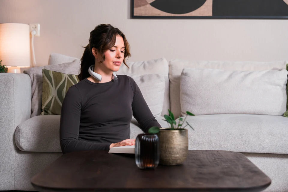 Woman sitting on a sofa wearing the MaxoRize Professional X around her neck